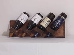 four bottles of wine are lined up on a wooden stand with two corks in the middle