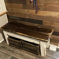 a wooden bench sitting in front of a wall with drawers underneath it and a coat rack on the side