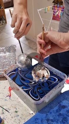 two people are working on something in a box with blue and white designs, one is holding a knife