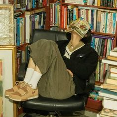 a woman sitting on a chair in front of a bookshelf filled with books