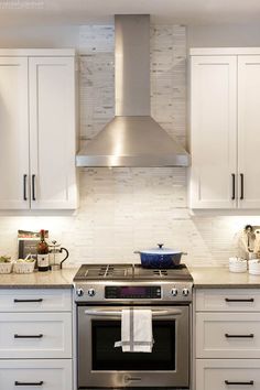 a stove top oven sitting inside of a kitchen next to white cupboards and drawers