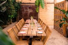 a long wooden table with plates on it in the middle of an outdoor patio area