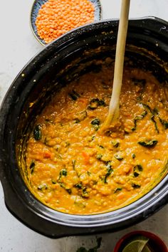 a pot filled with soup next to two bowls full of beans and other food items