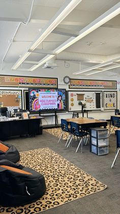 an empty classroom with chairs, desks and large television screens on the wall above them