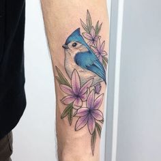 a blue bird with pink flowers on its arm