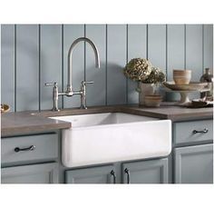 a kitchen with gray cabinets and white sink