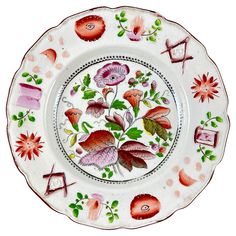 a plate with flowers and leaves painted on the side, in pinks and greens