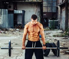 a man with no shirt is holding a barbell