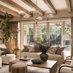 a living room with couches, chairs and a coffee table in front of two windows