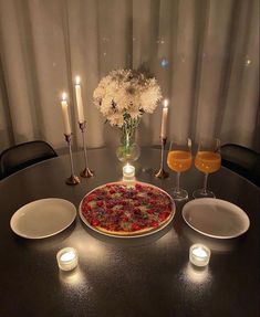 a table topped with a pizza covered in toppings next to two glasses of wine