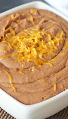 a white bowl filled with brown dip and cheese