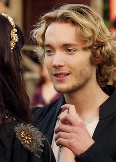 a young man is standing next to an older woman who is wearing a tiara