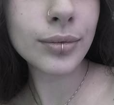 a close up of a person wearing a necklace and piercings on her nose,