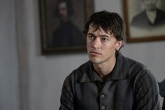 a young man sitting in front of a painting