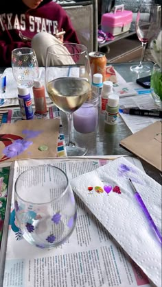 there is a glass of wine on the table with other crafting supplies around it