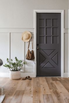 a door with a hat on it next to a potted plant and a purse