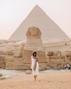 a woman is standing in front of the pyramids