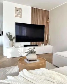 a living room with white furniture and a large flat screen tv mounted on the wall