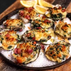 a plate full of cooked oysters with lemon wedges