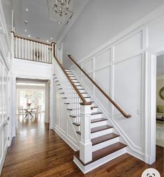 a white staircase with wooden handrails in a home's entryway area