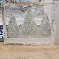 an old window frame is decorated with silver glitter christmas trees and snow on the ground