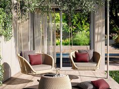 two wicker chairs sitting on top of a rug next to a swing chair and tree