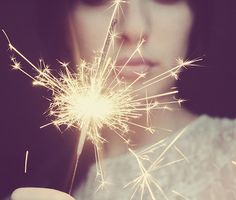 a woman holding a sparkler in her hand with it's light shining brightly