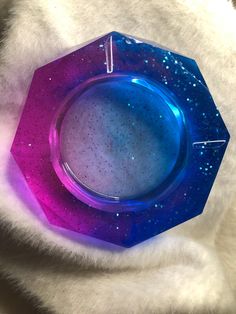 a purple and blue plate sitting on top of a white fur covered surface with space in the center