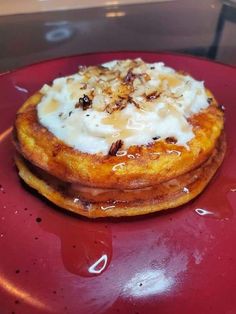 a red plate topped with pancakes covered in whipped cream