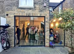 a group of people sitting at tables in front of a brick building with glass doors