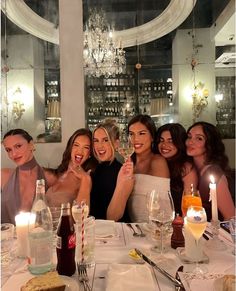 a group of women sitting at a table with wine glasses and candles in front of them