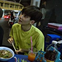 two young men sitting at a table with food and drinks in front of their faces