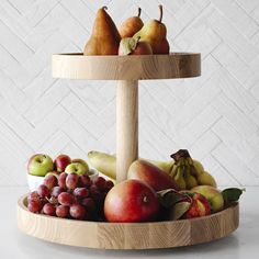 there is a wooden tray with fruit on it and two pears in the middle