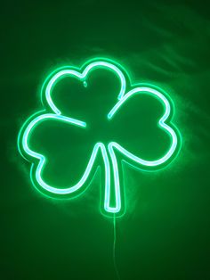 a green neon sign with a four leaf clover