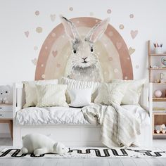 a white bed with pillows and stuffed animals on the floor in front of a wall mural