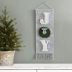 a christmas decoration hanging on the wall next to a potted tree