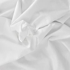 an unmade bed with white sheets and pillows