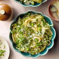 two bowls filled with pasta and peas on top of a table next to other dishes