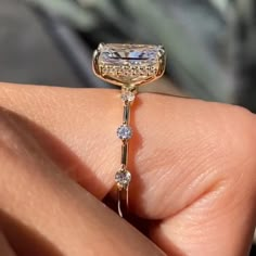 a close up of a person's hand holding an engagement ring