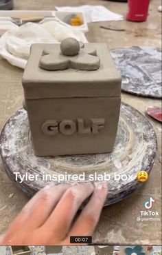 someone is making a clay sculpture with the word golf on it and an image of a man's hand