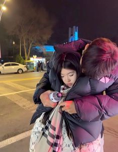 two people hugging each other on the street