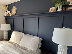 a bedroom with blue walls and white bedding, two lamps on either side of the bed