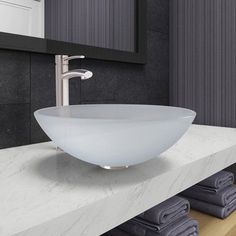 a bathroom sink sitting on top of a white counter next to towels and a mirror