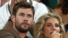 a man and woman sitting next to each other in the stands at a tennis match