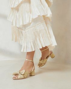 Pleated knot mid-heel sandal in gold lam. Padded footbed with gold stamped logo. Open toe, slips on with adjustable buckle ankle strap. 2 inch heel. Gold Bridal Shoes, Bridal Shoe, Autumn Bride, Mid Heel Sandals, Bow Heels, Loeffler Randall, 2 Inch Heels, Heel Sandal, Leather Pieces