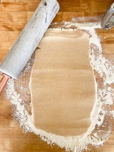 a rolling dough on a wooden table next to a rolling pin