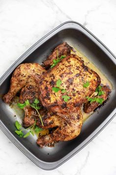 a roasting pan filled with chicken and garnished with parsley