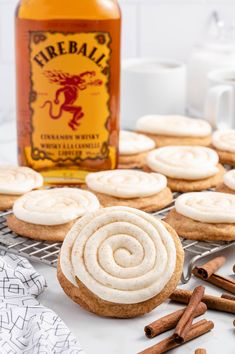 cinnamon spice cookies with vanilla frosting on a cooling rack next to a bottle of fireball