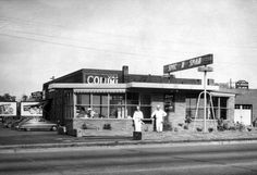 an old black and white photo of two people standing in front of a building that says colley's