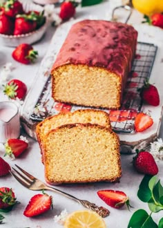 two slices of lemon pound cake sitting on top of a table next to sliced strawberries